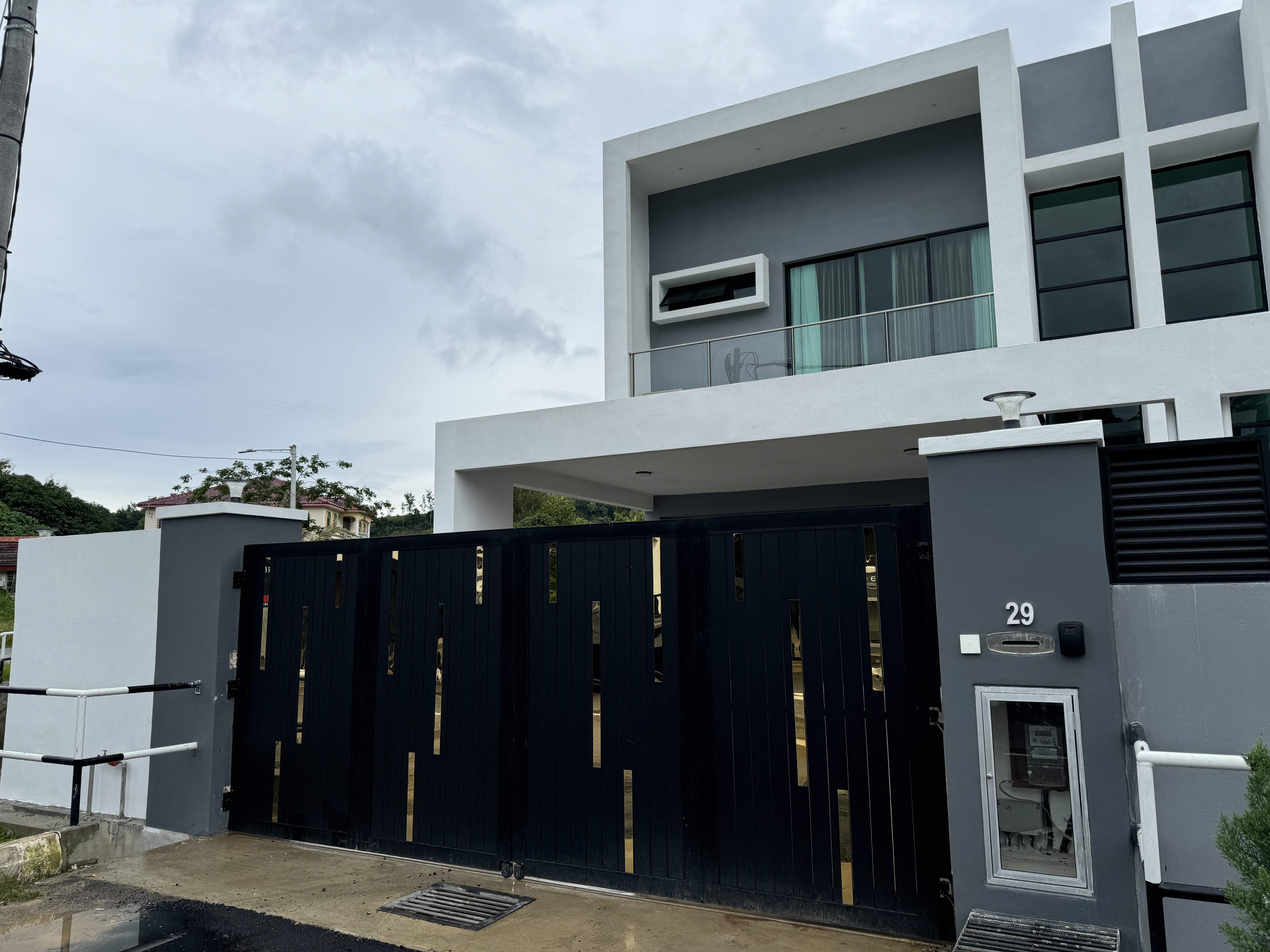Contemporary grey villa exterior in Langkawi with gold gate — vacation rental managed by BNB Management